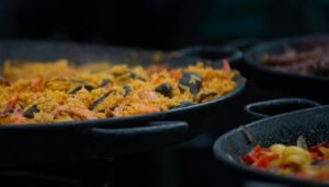Appetizing close-up of traditional seafood paella cooking in a large outdoor pan.